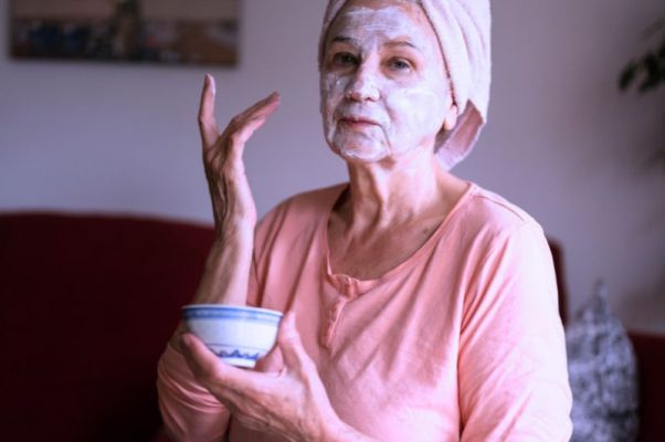 Older woman in bathrobe with  face mask